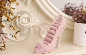 Macro detail of a pink high heel ring display stand with soft fabric cushioning