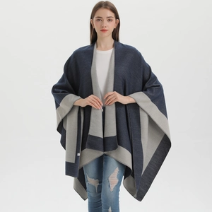 Detail of soft knit poncho with dark blue and grey geometric patterns on a model
