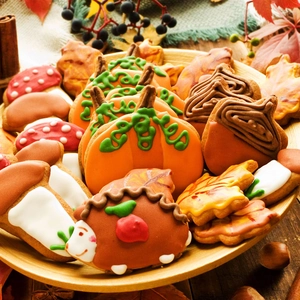 Close-up of Thanksgiving cookies with pumpkin and maple leaf icing on a wood tray