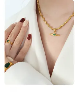 Detail of vintage gold twisted chain necklace and ring with rectangular green emerald stone