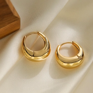 Minimalist gold-plated geometric C-shaped hoop earrings on elegant silk background