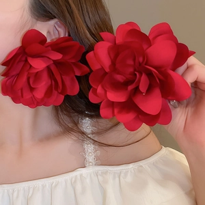 Close-up of a large red layered mesh petal earring worn by a model for a beach holiday look