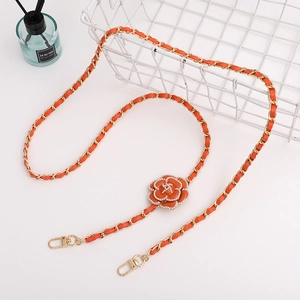 Detail of orange leather gold chain strap featuring camellia flower and pearl accent