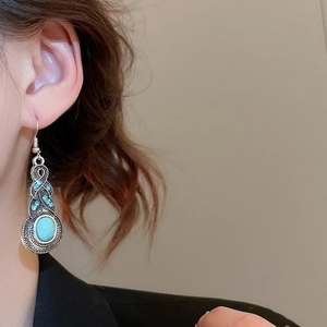 Close-up of vintage silver bohemian tassel earrings with oval turquoise and leaf detail