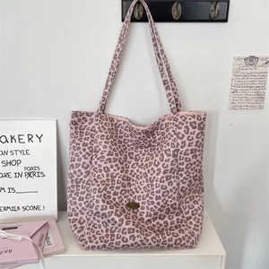Macro detail of leopard print canvas tote with metallic logo badge and pink interior