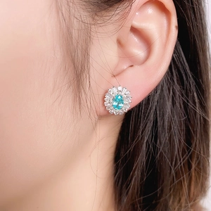 Close-up of a floral blue oval gemstone stud earring worn by a model in soft light