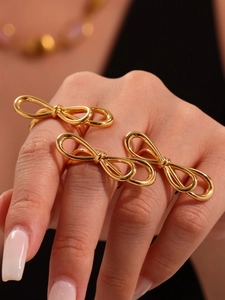 Close-up of minimalist gold bow rings layered on fingers with 18k gold plating finish