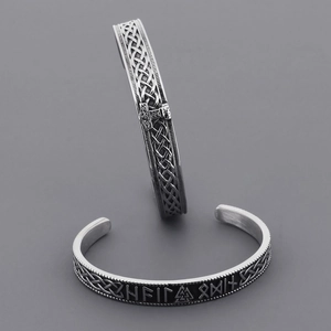 Macro detail of silver Viking cuff bracelet with Norse runes and Celtic knots