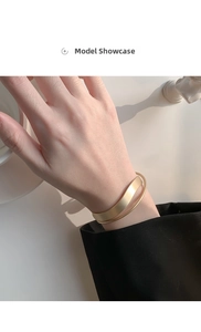 Dettaglio del bracciale rigido a doppio strato oro opaco con trama in metallo spazzolato