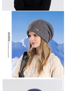 Détail d'un bonnet en tricot gris avec écusson en cuir sur fond de paysage enneigé