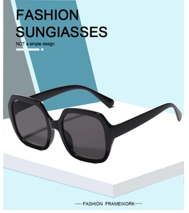 Close-up of oversized black square sunglasses displayed on a geometric minimal stand