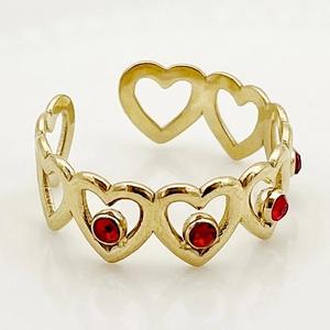 Detail view of a gold-plated heart chain ring with red gemstones and adjustable open band