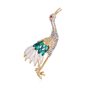 Detailed macro shot of elegant golden crane brooch with white enamel and green crystals