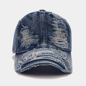Close-up of heavy distressed ripped details on a dark blue vintage denim baseball cap