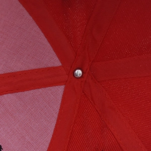 Close-up of the red baseball cap interior showing reinforced stitching and metal rivet