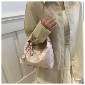 Detail of pink silk jacquard handbag featuring pearl drawstring and floral embroidery texture