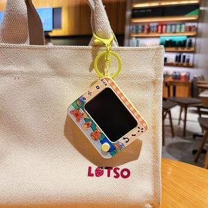 Cute cartoon capybara TV keychain hanging on a beige canvas bag in a cafe setting