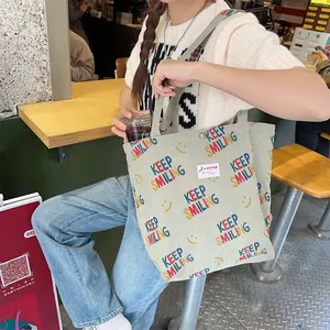Green corduroy tote bag detail showing the colorful Keep Smiling text and yellow smiley face