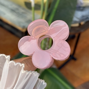 Gros plan sur la pince à cheveux fleur rose avec texture transparente et ressort
