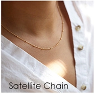 Gros plan d'un collier chaîne satellite dorée porté par un mannequin en chemise blanche