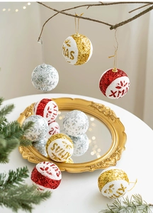 Detail of glittery and flocked Christmas ball ornaments with XMAS text on a tray