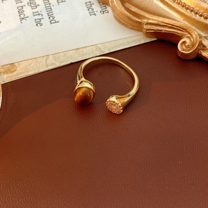 Gros plan d'une bague dorée en œil de tigre avec zircone sur un fond de cuir vintage