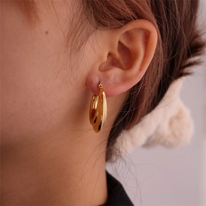 Close-up of chunky gold hoop earring on model with a minimalist aesthetic style