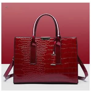Detailed view of glossy red crocodile pattern handbag with polished metal buckles