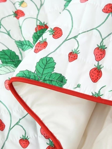 Detailed macro view of quilted white cotton fabric with vibrant red strawberry prints