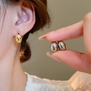 Close-up of sleek gold and silver teardrop earrings showing fit and glossy metal finish