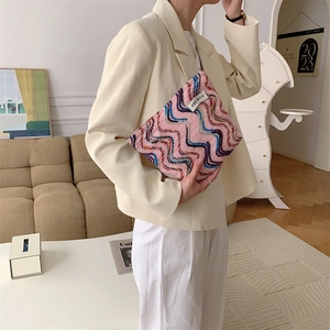 Close-up of rainbow wave knit canvas pouch with colorful embroidery and side label