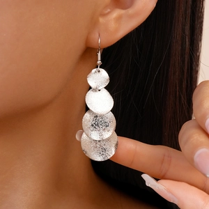 Boucles d'oreilles pendantes rondes géométriques argent mat sur modèle style moderne