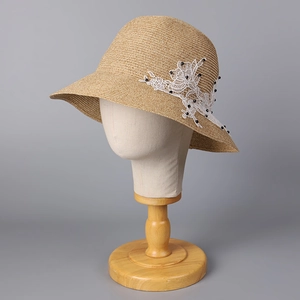 Close-up of wide brim straw hat featuring elegant white lace floral embroidery and beads
