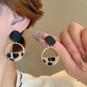 Detail showing gold-plated leopard print star earrings with plush texture on model