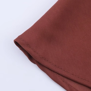 Gros plan sur la texture du tissu brun-rouge et les coutures de la robe midi chic