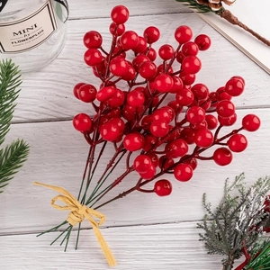 Detail of red artificial holly berry bunch with pine cones on white wooden background