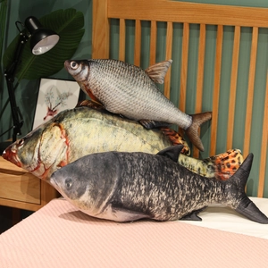 Three realistic plush fish pillows in various sizes displayed in a cozy bedroom setting