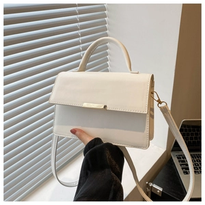 White minimalist square handbag held by a model in a stylish office setting with soft lighting