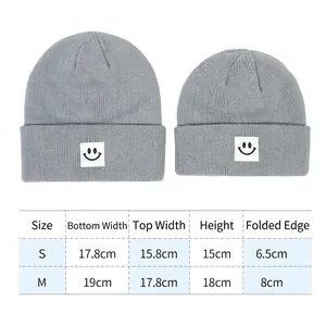 Berretto in maglia grigia con patch smiley e tabella delle taglie per S e M