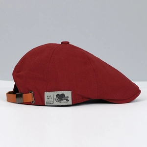 Detail view of burgundy canvas beret hat with adjustable leather strap and metal buckle