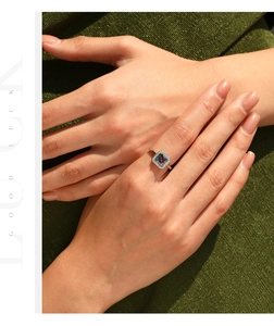 Macro shot of silver ring featuring square iridescent gemstone with diamond halo detail