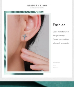 Detail of silver vintage cross stud earrings with turquoise blue stone on model ear