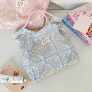 Détail de la broderie de papillons en dentelle sur des sacs cabas bleu clair et rose