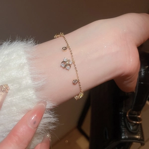 Exquisite gold chain bracelet with sparkling zircon flower charm on model's wrist