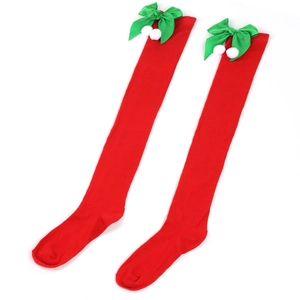 Detail of red Christmas over-knee socks featuring green bows and white fuzzy balls