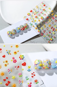 Detailed close-up of 5D embossed nail stickers featuring colorful cartoon sun and flowers