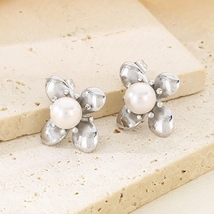 Detailed macro view of silver flower earrings featuring white pearls on a stone base