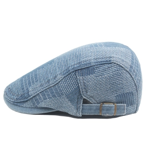 Detail of blue textured denim ivy cap showing adjustable metal buckle and stiff fabric