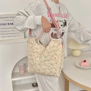 Close-up of quilted cream tote bag with cute bear patterns and woven pink handles