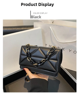 Detail of black quilted leather texture and chunky black-gold chain on handbag